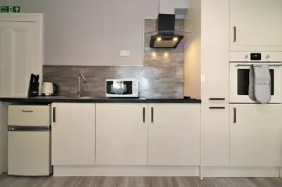 a kitchen with white cabinets and a microwave at Signature - Linden House Flat 4 in Airdrie