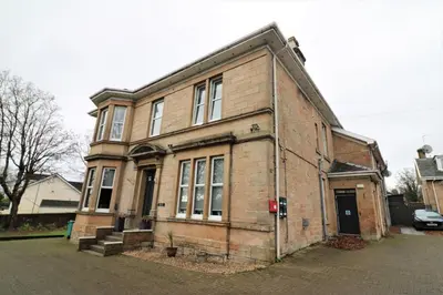 an old brick building sitting on the side of a street at Signature - Linden House Flat 4 in Airdrie