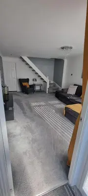 a living room with two beds and a staircase at Beautiful 2 bed house close to M74 and Strathclyde Park in Motherwell