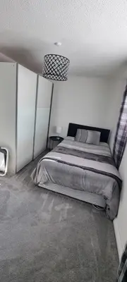 a bedroom with a bed in a white room at Beautiful 2 bed house close to M74 and Strathclyde Park in Motherwell