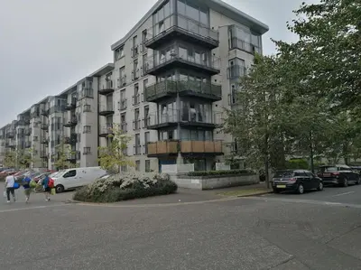 a tall building with cars parked in a parking lot at Fabulous 3 Bedroom Flat in Edinburgh