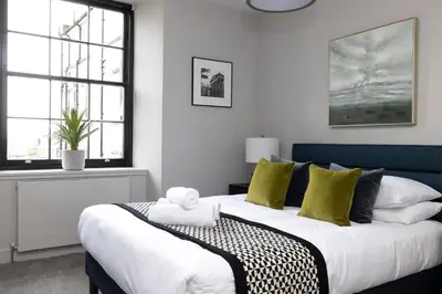a bedroom with a large bed with green and white pillows at JOIVY Stylish Flat in New Town in Edinburgh