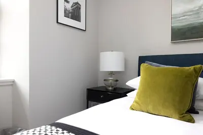 a bedroom with a bed with a yellow pillow and a lamp at JOIVY Stylish Flat in New Town in Edinburgh