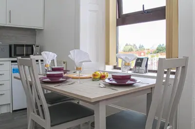 a dining room table with two chairs and a table with wine glasses at Station Signature Apartment near Lanark in Carstairs