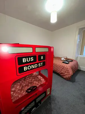a red suitcase in a room with a bed at Station Signature Apartment near Lanark in Carstairs