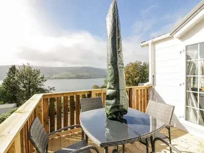 a table and chairs on a deck with a view of the water at 11 Mansion View in Helensburgh