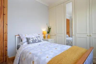 a white bedroom with a bed and a mirror at Bay View in Lochgilphead