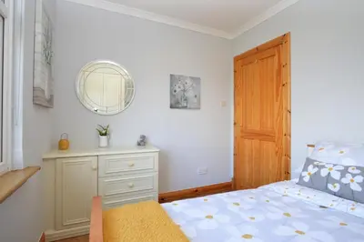 a bedroom with a bed and a dresser and a mirror at Bay View in Lochgilphead
