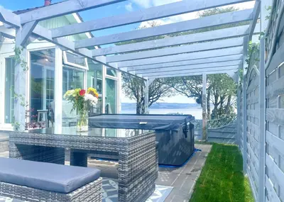 a patio with a glass table and a pergola at Bay View in Lochgilphead
