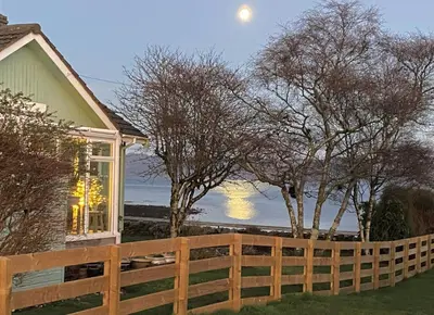 a fence in front of a house with the moon in the sky at Bay View in Lochgilphead