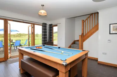 a billiard table in a living room with a staircase at Kennacraig Lodge in Whitehouse