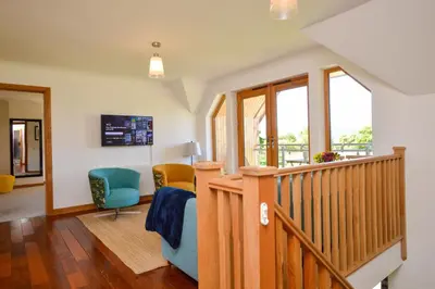 a living room with a staircase and two chairs at Kennacraig Lodge in Whitehouse