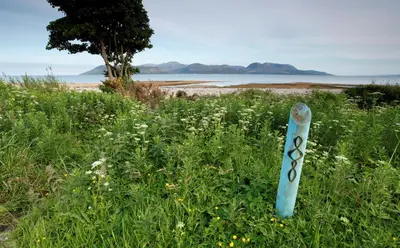 a blue pole in the grass next to a beach at Kennacraig Lodge in Whitehouse