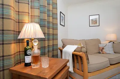 a living room with a couch and a bottle of wine on a table at Kennacraig Lodge in Whitehouse