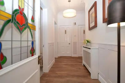 a hallway with white walls and floors and a hallway with paintings at Glen Oirig in Hunters Quay