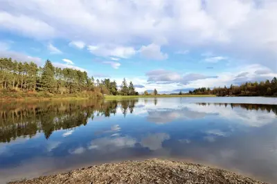 a large lake with trees and clouds in the water at Glen Oirig in Hunters Quay