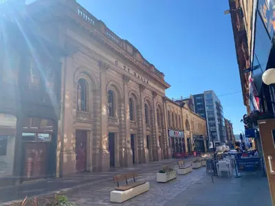 a building on a city street with benches in front at Lovely 1-Bed Apartment in Glasgow Merchant City in Glasgow