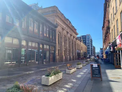 an empty city street with buildings and a sign at Lovely 1-Bed Apartment in Glasgow Merchant City in Glasgow