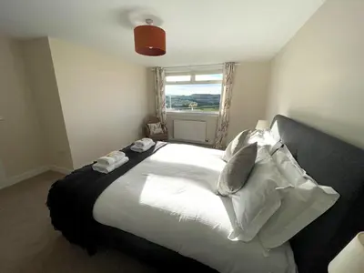 a bedroom with a large white bed with a window at Beautiful 5BR Rural Cottage with Outstanding Views - Pass the Keys in Castle Douglas