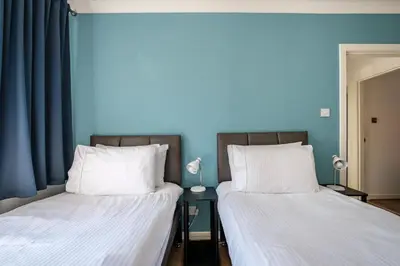 two beds in a room with blue walls at The Douglas - Spacious 2 bed apartment in Uddingston in Uddingston