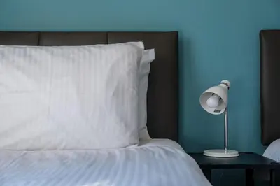 a bed with a white pillow and a lamp on a table at The Douglas - Spacious 2 bed apartment in Uddingston in Uddingston