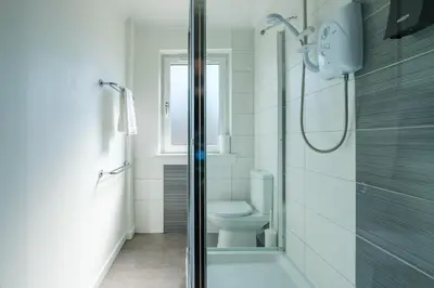 a white bathroom with a shower and a toilet at The Douglas - Spacious 2 bed apartment in Uddingston in Uddingston