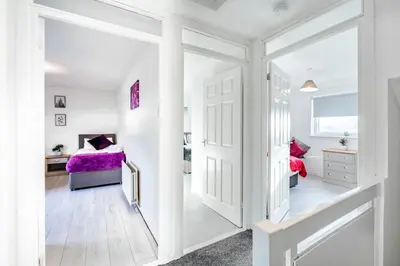 a white hallway with a door leading to a bedroom at Balloch House -Spacious 3 bed house with on street parking in Kirk of Shotts