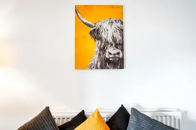a painting of a cow on a wall next to pillows at Balloch House -Spacious 3 bed house with on street parking in Kirk of Shotts