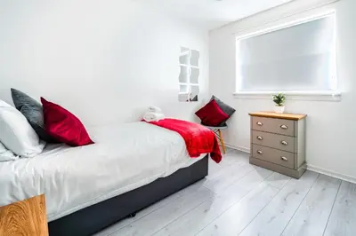 a bedroom with a bed with red pillows and a window at Balloch House -Spacious 3 bed house with on street parking in Kirk of Shotts