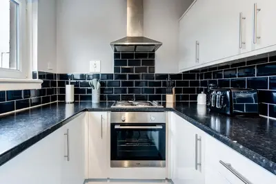 a kitchen with white cabinets and a stove top oven at Balloch House -Spacious 3 bed house with on street parking in Kirk of Shotts