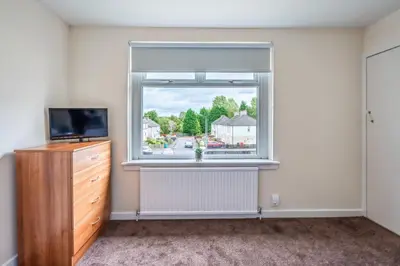 a room with a window with a television and a dresser at Millfield House - Cosy 2 bed house in Motherwell in Motherwell