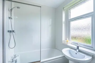 a white bathroom with a shower and a sink at Millfield House - Cosy 2 bed house in Motherwell in Motherwell