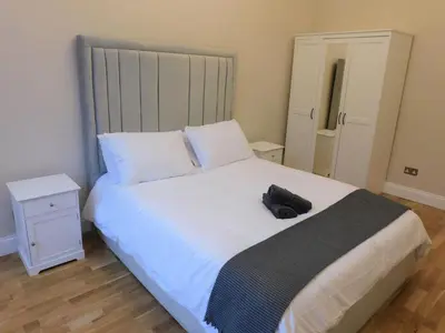 a bedroom with a large white bed with a hat on it at Beautiful 3 bed apt in the City Centre in Glasgow