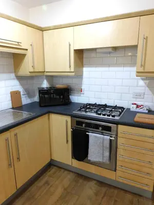 a kitchen with wooden cabinets and a stove top oven at Fabulous 2 bed apt 10 mins from City Centre in Glasgow
