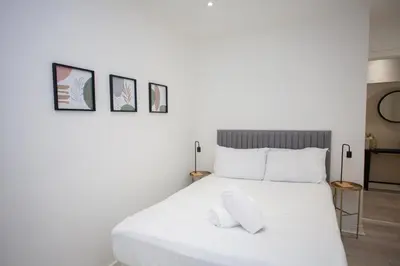 a bedroom with a white bed with three pictures on the wall at Bright Central Flat with Balcony and Free Parking in Glasgow