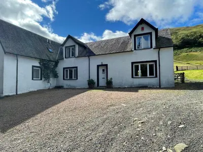 a white house with a gravel driveway in front of it at Exclusive private estate cottage in Lochearnhead