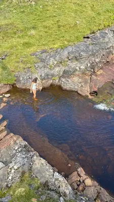 a woman is standing in a body of water at Exclusive private estate cottage in Lochearnhead