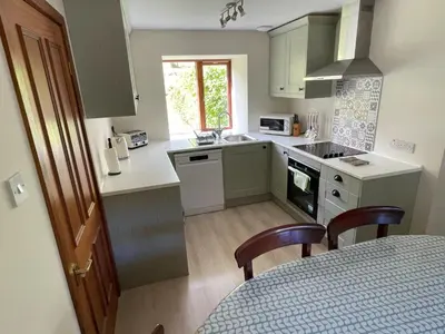 a kitchen with green cabinets and a table with chairs at Exclusive private estate cottage in Lochearnhead