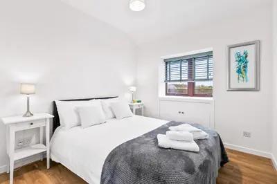 a white bedroom with a bed with two towels on it at Aspen Apartment in Helensburgh