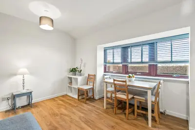 a dining room with a table and chairs and a window at Aspen Apartment in Helensburgh