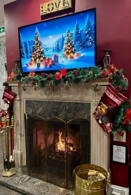 a fireplace with a television above it with christmas decorations at FINN VILLAGE 