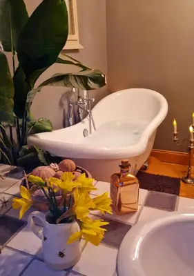 a bathroom with a sink and a bath tub with flowers at Fyne Byre Cottage - Barn Conversion with Hot Tub in Cairndow