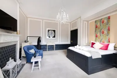 a bedroom with a large bed and a blue chair at JOIVY Contemporary Flat in the New Town in Edinburgh