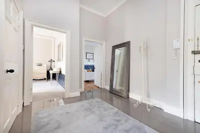 a white hallway with a mirror and a bedroom at JOIVY Contemporary Flat in the New Town in Edinburgh