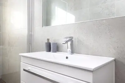 a bathroom with a white sink and a mirror at JOIVY Contemporary Flat in the New Town in Edinburgh
