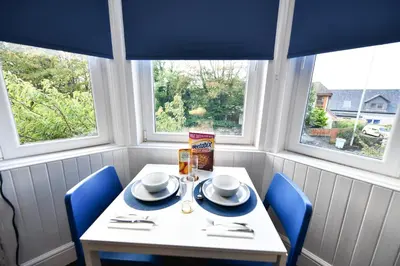 a white table with blue chairs in a room with windows at The Wee Lion in Troon