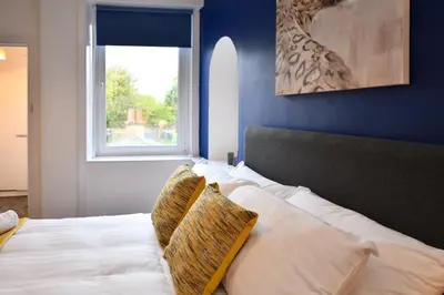 a bedroom with a white bed with a window at The Wee Lion in Troon