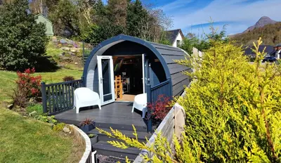 a blue shed with two white chairs on a wooden deck at Bothan Creag Sobhrag in Ballachulish