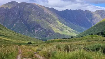 a mountain range with a dirt road in a field at Bothan Creag Sobhrag in Ballachulish