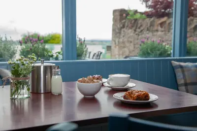 a wooden table with two plates of food and milk at Coorie in Dunfermline